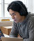 Un jeune homme portant un casque audio étudie l'anglais sur une tablette dans un intérieur lumineux.