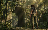 Lara Croft debout de dos devant une arche de pierre ancienne recouverte de végétation dans une jungle luxuriante.