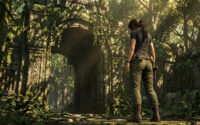Lara Croft debout de dos devant une arche de pierre ancienne recouverte de végétation dans une jungle luxuriante.