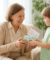 Un jeune garçon souriant offre un cadeau emballé avec une carte en forme de cœur à sa grand-mère souriante.
