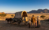 Une famille boer avec un chariot bâché traditionnel face aux vastes plaines d'Afrique du Sud.
