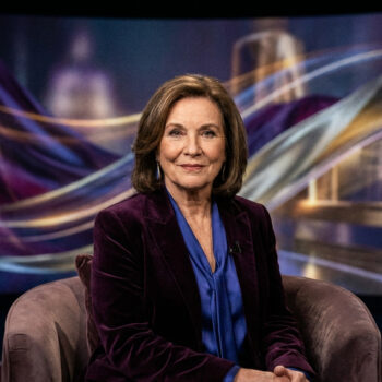 L'actrice Imelda Staunton assise dans un fauteuil devant un écran aux reflets violets et dorés.