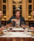 Un homme expressif au centre d'une table, entouré d'invités lors d'un dîner élégant, évoquant le film Le Dîner de cons.