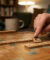 Une main place une lettre K sur un plateau de jeu en bois pour former des mots commençant par la lettre K.