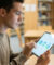 Étudiant concentré utilisant une tablette avec des icônes d'e-mail, de réglages et de cadenas dans une bibliothèque.