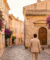 Un homme marche dans une ruelle pavée ensoleillée de Saint-Tropez, bordée de maisons colorées et de bougainvilliers.