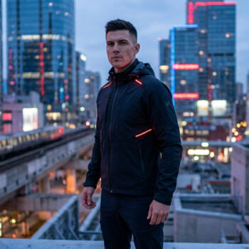 Un homme à la coiffure soignée portant une veste tactique avec des détails lumineux dans une ville futuriste.