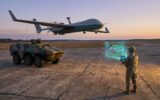 Un soldat utilise une tablette pour piloter un drone de reconnaissance au-dessus d'un véhicule blindé au coucher du soleil.