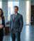 Un homme et une femme en tenue professionnelle posant dans un bureau moderne et lumineux.