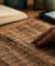 Main touchant un papyrus ancien avec un livre et une tablette en arrière-plan.