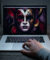 Un ordinateur portable affichant un masque dramatique style Phantom of the Paradise sur un bureau en bois sombre.