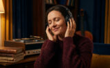 Femme écoutant de la musique avec un casque audio les yeux fermés dans un salon confortable.