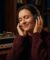 Femme écoutant de la musique avec un casque audio les yeux fermés dans un salon confortable.