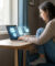 Une femme utilisant un ordinateur portable avec des icônes numériques de sécurité, de cadenas et d'e-mails à l'écran.