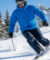 Skieur en veste bleue et pantalon noir dévalant une piste enneigée en montagne.