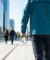 Un homme marche dans une rue moderne en consultant l'application Mappy sur son smartphone pour s'orienter.