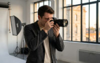 Un photographe professionnel avec son appareil photo dans un studio lumineux avec vue sur Bordeaux.